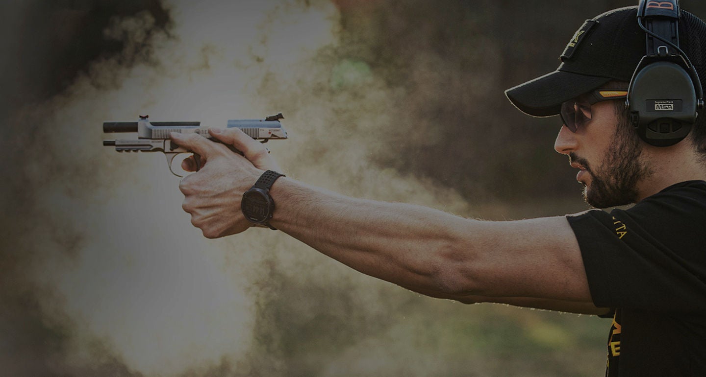 A man taking aim with a gun at a target in a USPSA match
